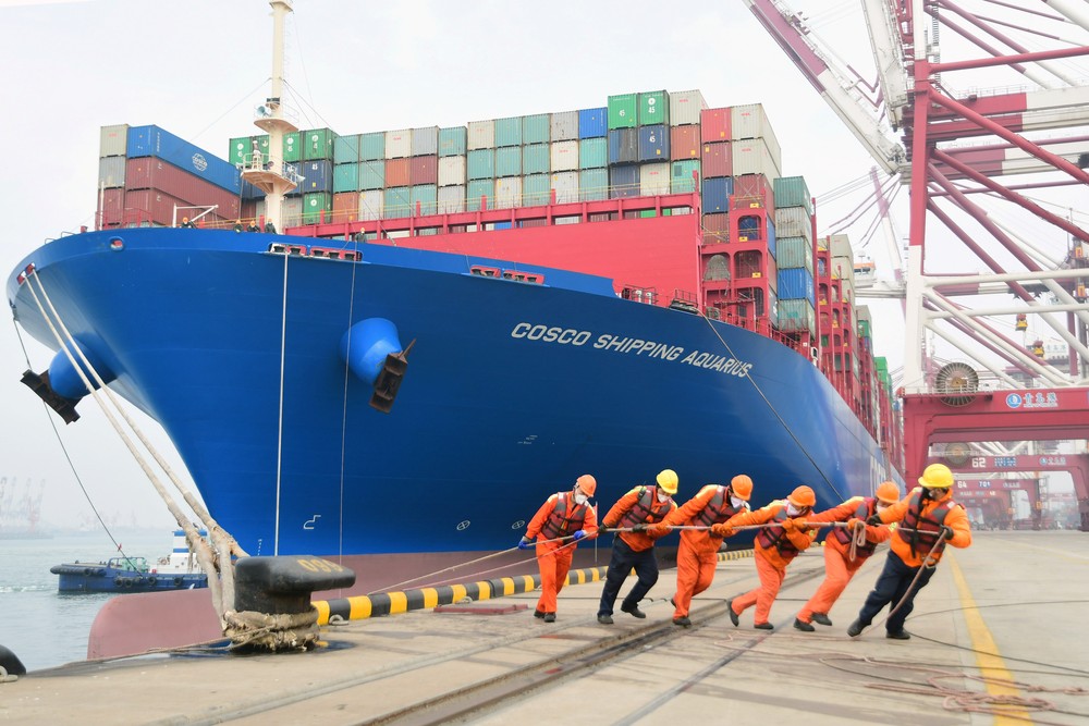 Exportações: Trabalhadores vestem máscaras enquanto trabalham no porto em Qingdao, na China — Foto: China Daily via REUTERS